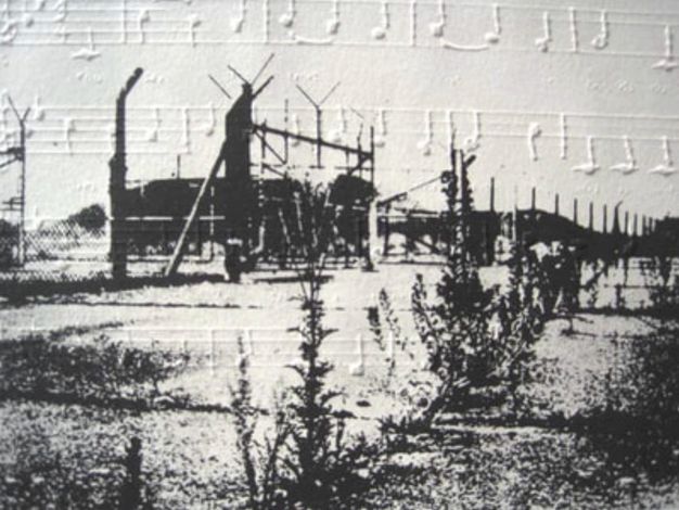 Black and white photograph of a complex behind a chain-link fence overlays or is overlaid with musical notation in raised white on white, so the notes and staff cast shadows.