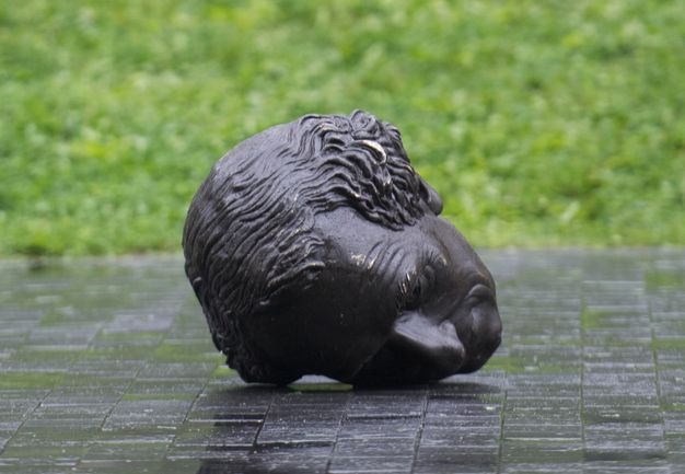 The bronze head of a statue is padded in layers of foam and blankets, and is strapped to the flatbed of a truck.